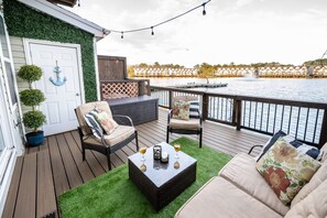 Um terraço com móveis de exterior, uma pequena mesa e vista para um corpo de água.