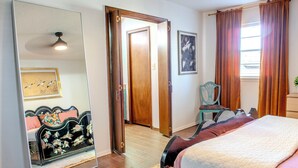 A bedroom with a bed, a large mirror, a wooden door, and a framed picture on the wall. - Game Room + Colorful Comfort (Norman)