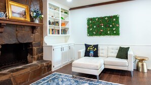 A living room with a stone fireplace, white shelves, a white sofa, and a decorative wall hanging. - Game Room + Colorful Comfort (Norman)
