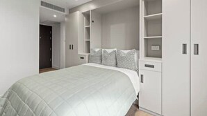 A bedroom with a large bed, built-in shelving, and a wardrobe.