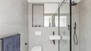 A modern bathroom with a toilet, sink, and glass shower enclosure.