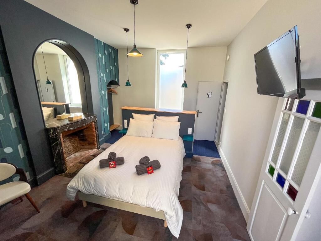 Un dormitorio con cama, espejo, cómoda, televisor y puerta con panel de vidrio esmerilado.
