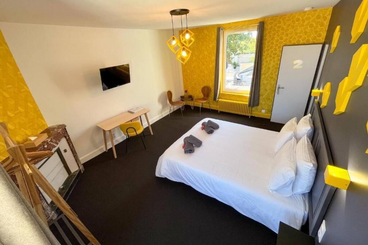A hotel room with a bed, a desk, a chair, a TV, and a window with a view.