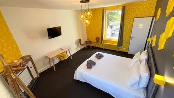 Ett hotellrum med en säng, ett skrivbord, en stol, en tv och ett fönster med utsikt.