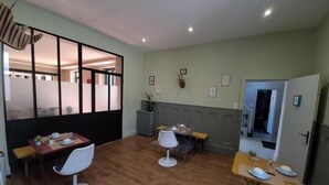 A dining area with wooden flooring, white chairs, and a table set for two. - La Longère de Neuville (Neuville-de-Poitou)
