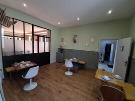 Uma sala de jantar com piso de madeira, cadeiras brancas e uma mesa posta para dois.