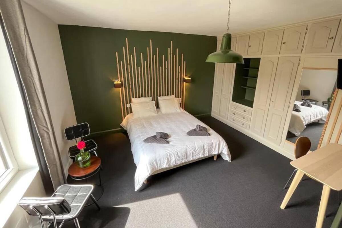 A bedroom with a bed, a desk, a chair, a wardrobe, and a mirror.