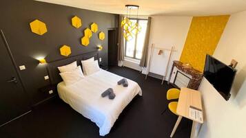 Quarto de hotel moderno com uma cama grande, uma escrivaninha e uma televisão.