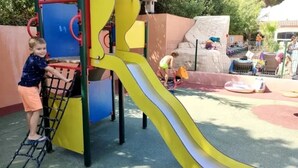 A playground with a slide, climbing structures, and a climbing wall.