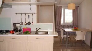 A compact kitchen with a sink, stove, and hanging utensils. There is a dining area with a table and chairs.
