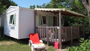 A mobile home with a porch and a red chair.
