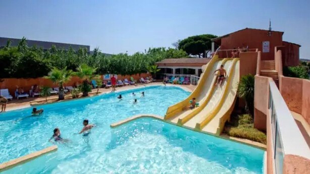 A swimming pool with a water slide and lounge chairs.