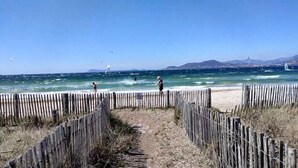 Ein Strand mit einer Holzlattenveranda, blauem Himmel und dem Ozean im Hintergrund.