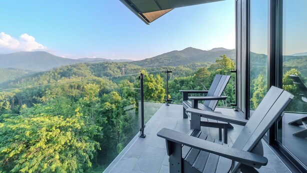 A balcony with two lounge chairs overlooking a mountainous landscape.