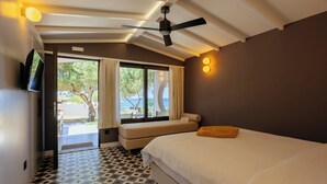 A hotel room with a bed, a ceiling fan, a TV, and a view of the outdoors. - Via Lassi bungalow 6 (Ioanian Islands)