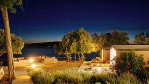 A nighttime outdoor area with a pathway, seating, and a view of the sea. - Via Lassi bungalow 6 (Ioanian Islands)