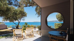 A terrace with a view of the sea, wooden furniture, and a round window. - Via Lassi bungalow 6 (Ioanian Islands)