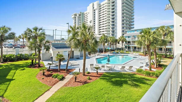 Un hotel con piscina, palmeras y vistas a un edificio alto.