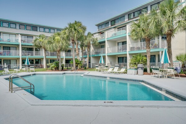 Ein Hotel mit Pool, Außenbereich und Palmen.