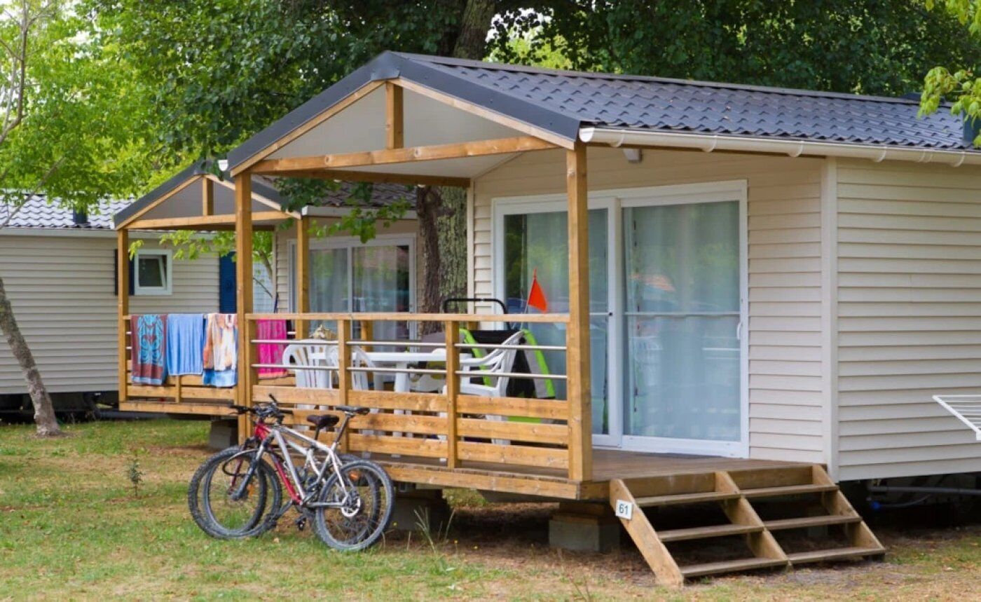 Een klein houten huisje met een veranda, een fiets en een trap naar de ingang.