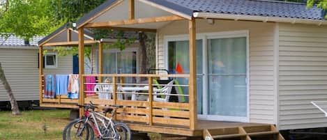 A small wooden cabin with a porch, a bicycle, and a set of stairs leading to the entrance.