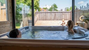 Un jacuzzi con una terraza de madera y una valla de madera al fondo.