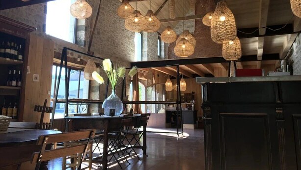 Un restaurant doté de luminaires suspendus en osier, d’un plafond en bois et offrant une vue sur l’extérieur.