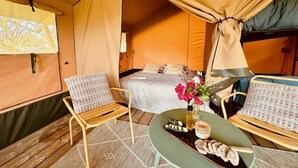 Une pièce aménagée avec une tente, comprenant deux lits, une table avec des collations et une chaise.