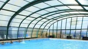 An indoor swimming pool with a curved glass ceiling.