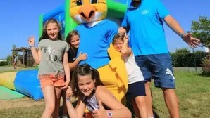 A group of people with a mascot in a grassy outdoor area.