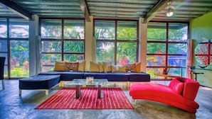 A modern living room with a sectional sofa, a red armchair, and a glass coffee table. - Arroyos Verdes (Bucerías)