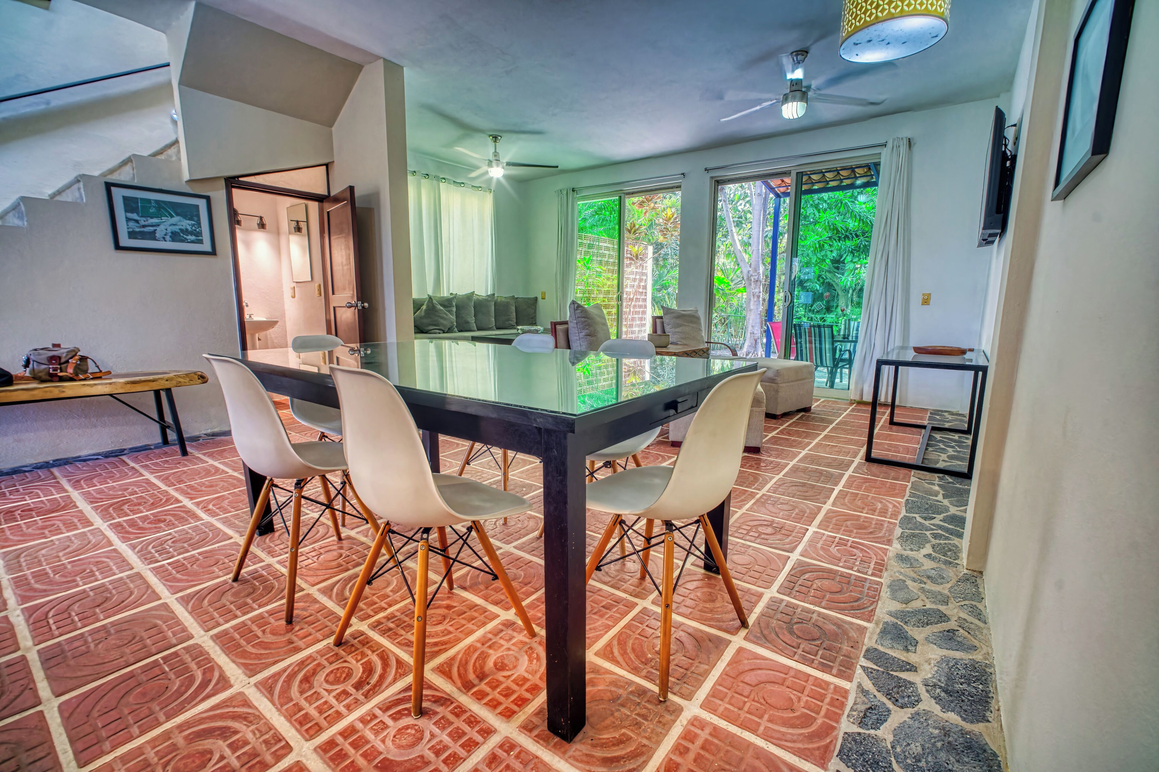 A dining area with a glass-top table, four chairs, and a patterned floor.