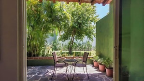 An outdoor patio with a table and chairs, surrounded by potted plants and a view of lush greenery. - Arroyos Verdes (Bucerías)