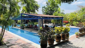A pool area with a covered seating area, potted plants, and a clear blue pool. - Arroyos Verdes (Bucerías)