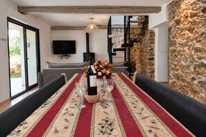 A dining area with a table set for two, a bottle of wine, and a vase of flowers.