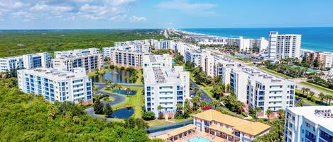 A high-rise hotel with multiple floors, a swimming pool, and a view of the ocean.