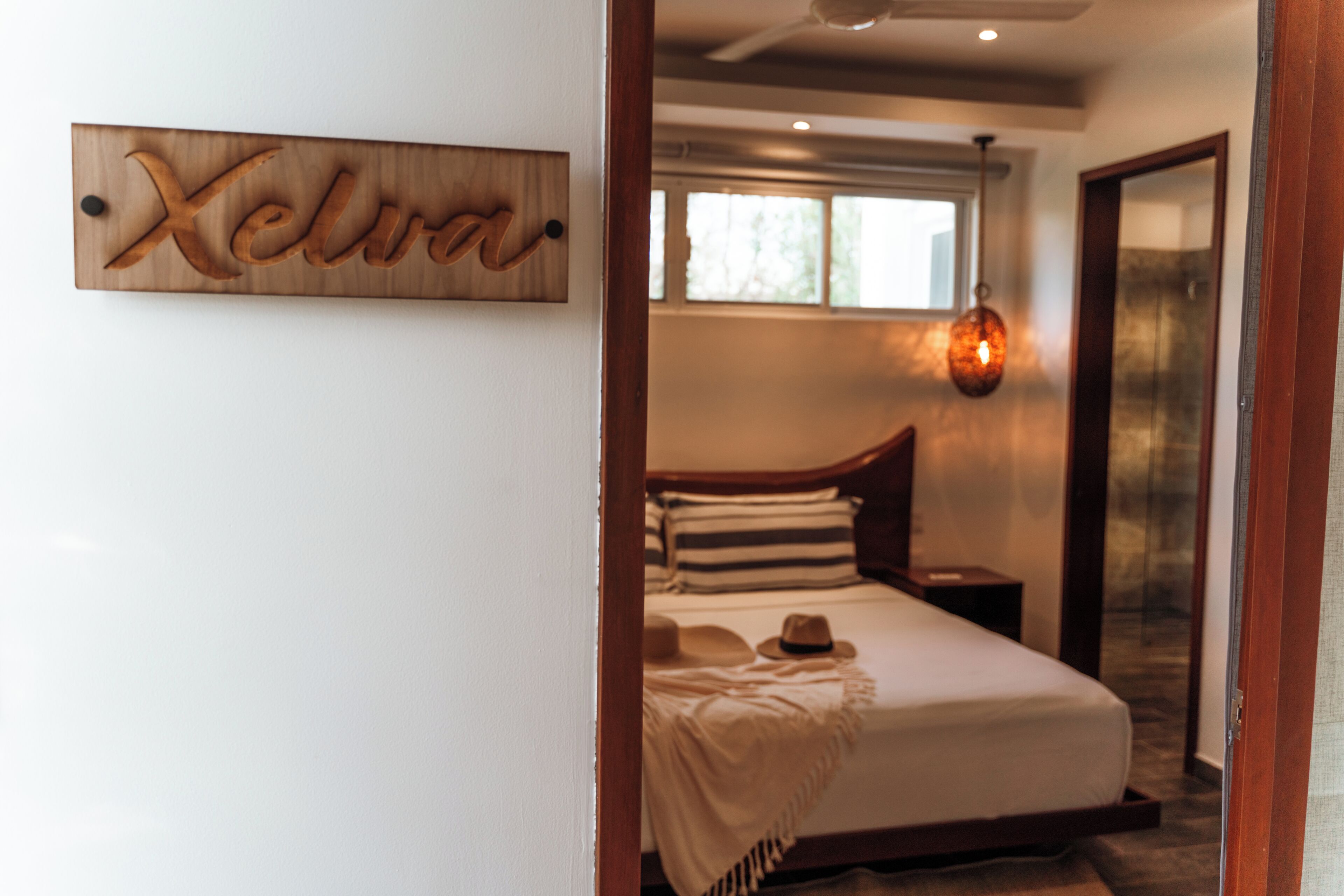 Een slaapkamer met een bed, nachtkastje, raam en een wandlamp.
