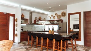Uma cozinha moderna com uma ilha central, banquetas e uma mesa de jantar.