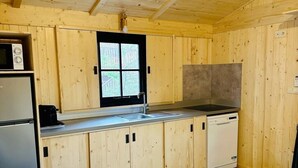 Kompakti keittiö, jossa on puukalusteet, sisäänrakennettu mikroaaltouuni ja astianpesukone.