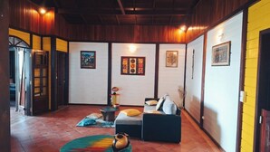 A cozy living room with a sofa, a coffee table, and a rug. There are framed pictures on the walls and a door with a window. - 3 Bedroom Villa in Le Robert (Le Robert)