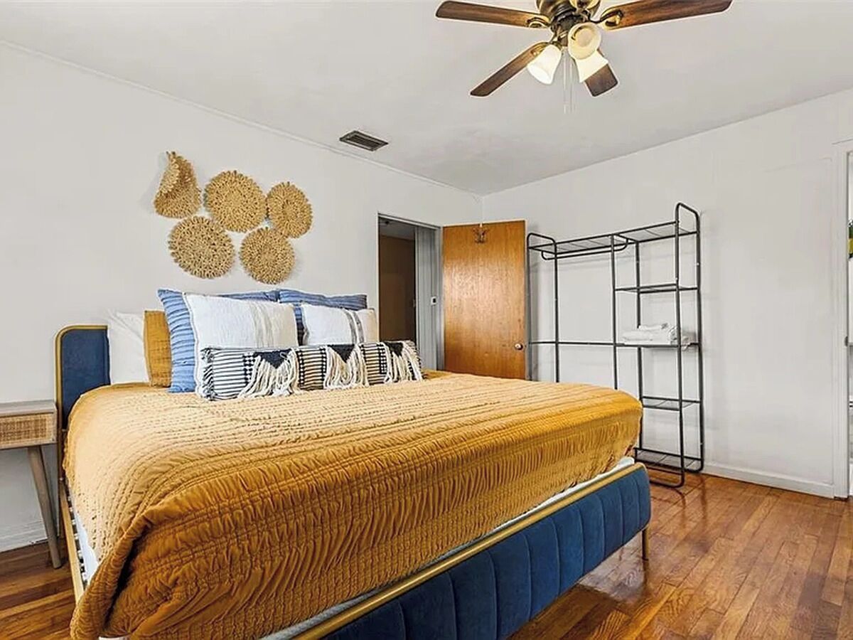 Ein Schlafzimmer mit Bett, Deckenventilator, Kleiderschrank und einer Metallregaleinrichtung.