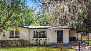 Une maison de plain-pied avec un porche à l’avant, un petit jardin et une zone couverte sur le côté droit.