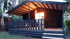 Une cabane en bois avec une véranda, un banc et un escalier menant à l’entrée.