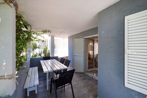 A patio with a wooden table and chairs, a sliding glass door leading to an indoor area, and a wall with a textured finish. - Bbq Holly Garden Novalja D (Novalja)