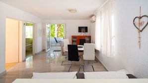 A modern living room with a dining area, a TV, and a heart-shaped decoration on the wall. - Bbq Holly Garden Novalja D (Novalja)