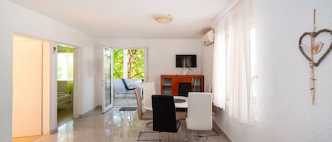 A modern living room with a dining area, a TV, and a heart-shaped decoration on the wall.