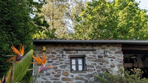 A stone building with a window, surrounded by greenery and trees. - Stone House Casa das Pedras (Vila Nova de Cerveira)