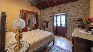 A bedroom with a bed, a wooden dresser, a stone wall, and a door. - Stone House Casa das Pedras (Vila Nova de Cerveira)
