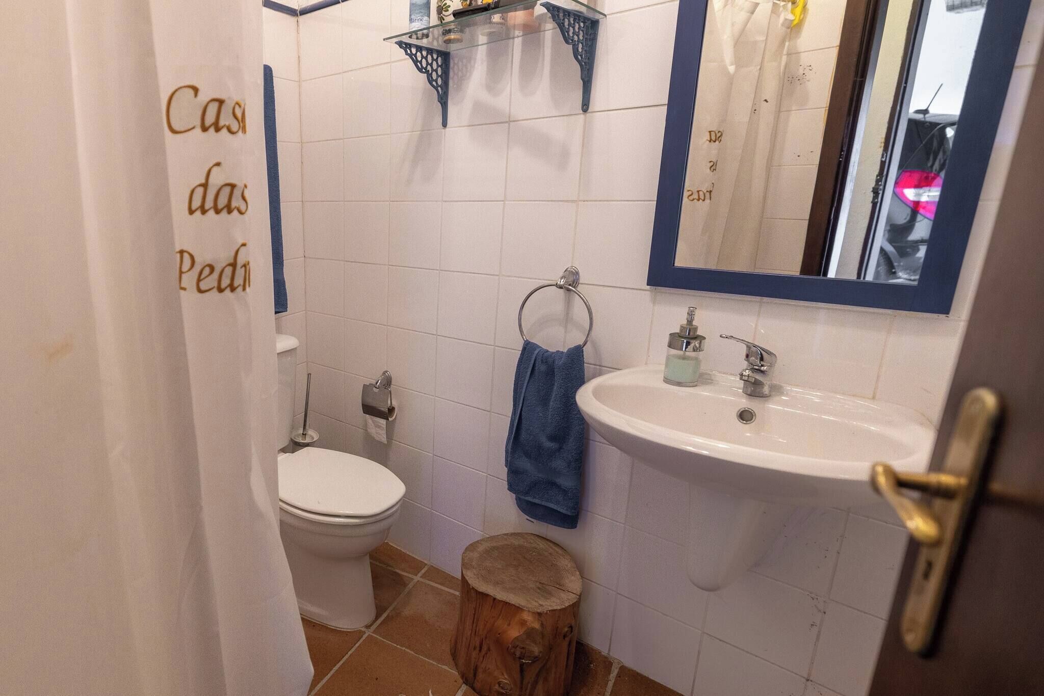 Une salle de bain équipée de toilettes, d’un lavabo, d’un miroir et d’une serviette accrochée au mur.
