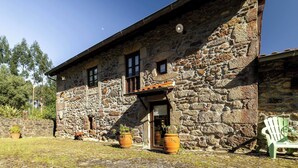 Un edificio de piedra con puerta de madera, dos ventanas y un pequeño balcón.
